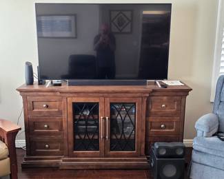 Large dark stain wooden media console with lattice glass-front cabinet doors, flanking drawers, and an Vizio flat-screen TV.