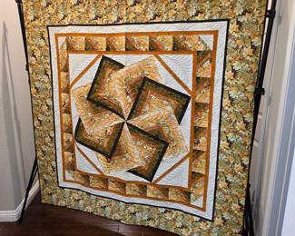 Full view of the "Farris Wheel" gold-and-green medallion quilt, showing its precise geometric composition, carefully aligned borders, and decorative quilting within the cream sections.