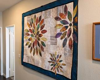 Handmade floral appliqué wall quilt with multicolored petals and dark border.