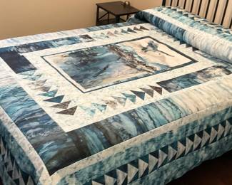 Angled view of the eagle quilt highlights its layered borders, repeated triangle units, decorative quilting, and coordinated blue, gray, and cream fabrics.