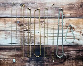 An assortment of chain necklaces and bracelets in gold-tone and silver-tone finishes, including rope, flat, and classic link styles.