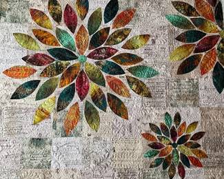Full composition of the floral appliqué quilt, featuring radiating blossoms, richly colored fabrics, and extensive custom quilting across the softly contrasting printed background.