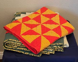 Red and golden-yellow patchwork quilt with precisely arranged triangles forming a lively pinwheel design. Coordinating binding completes the colorful geometric composition.
