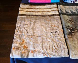 Woodland owl quilt with a printed wildlife panel, coordinating pieced borders, and flowing scroll quilting that adds texture throughout the softly colored design.