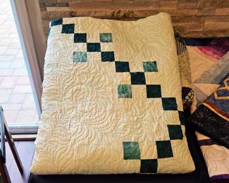 Handmade cream and green patchwork quilt with intricate feather quilting.