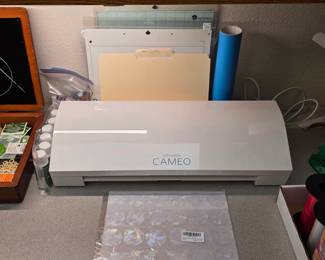 Silhouette Cameo electronic cutting machine with cutting mats and craft materials.
