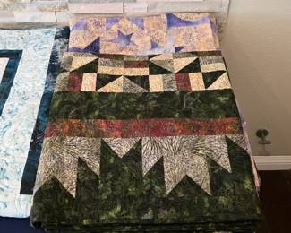 Woodland-inspired patchwork quilt with evergreen tree shapes, triangle piecing, and contrasting bands of forest green, cream, and earthy red-brown fabrics.