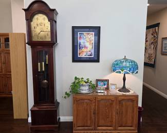 Traditional wooden grandfather clock with pendulum and decorative dial.