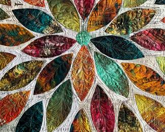 Close-up of a floral appliqué center: individual petals contain different feather, scroll, and leaf-like quilting patterns, highlighting the attention given to each section.