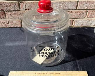 A80 - $55. Tom’s Toasted Peanuts Glass Jar. Measures 10 inches tall. It has some small scratches on the inner rim of the glass.