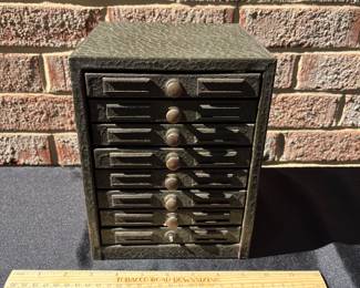 A86 - $150. Eight drawer metal pharmacy cabinet with labels. (Missing one knob) measures 6.5” x 6.5”x 8.5”.