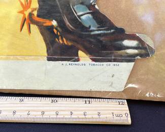 A6 - $80. Cavalier Cigarettes, die-cut counter display sign. Made in 1952. Measures 28 inches tall. Slight bending and creases on the hat and boot otherwise in great, vintage shape.