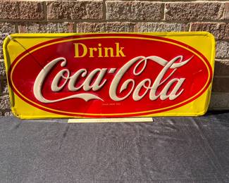 A40 - $325. 1950s Canadian red and yellow Coca-Cola sign. Measures 29.5” x by 12.25”. Some bent and creased metal.