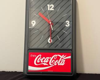 A133 - $30. 1989. Enjoy Coca-Cola wall clock. Measures 13" x 21.5" tall. Needs battery. Face has some scuffs.
