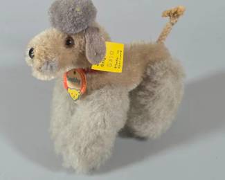 Vintage Steiff "Snobby" grey poodle plush toy from the 1950s to 1960s. has jointed legs, a wool pom-pom topknot and its original chest tag and yellow paper/button label