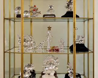 Collection of crystal figurines in a glass cabinet with gold trim