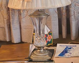 traditional cut-crystal and metal table lamp featuring a clear geometric-faceted crystal body, a fluted metal base and neck, and a pleated white fabric lampshade