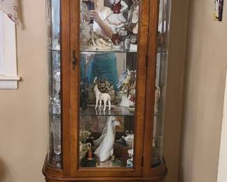 wood-framed lighted curio cabinet with curved/bowed glass sides