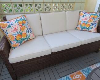 Three seat outdoor couch with cushions and weather cover.