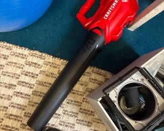 Handheld electric blower with a red housing and long black nozzle.