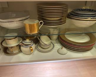 Assorted coordinated dishes, cups, saucers, and plates in a display cabinet.