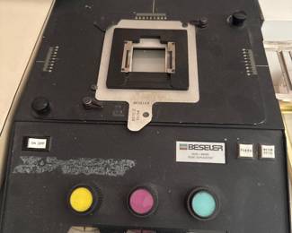 Film editing or splicing equipment with a metal film gate and colored controls.