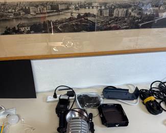 Long framed panoramic cityscape above cameras and small electronics.