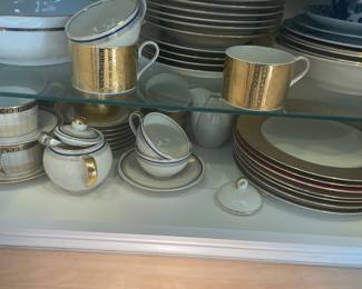 Matching gold-accented cups and saucers with coordinated dinnerware.