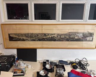 Long framed panoramic cityscape displayed above an assortment of electronics.