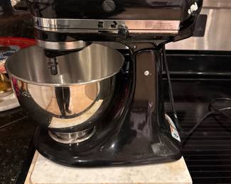 Black stand mixer with stainless-steel mixing bowl.