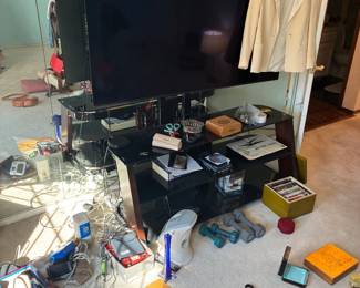 Flat-screen television and glass entertainment stand with electronics and accessories.