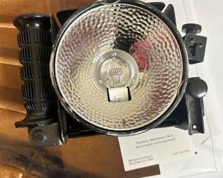 Round reflector-style photographic light with accessory components.