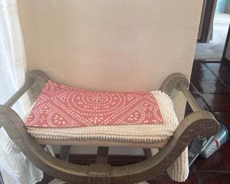 Decorative upholstered bench with curved wooden arms and a patterned cushion.