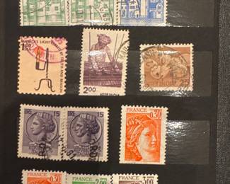 Assorted postage stamps with portraits and illustrated designs on a black album page.