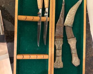 Decorative knives and sheaths displayed in green-lined wooden cases.