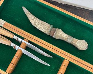 Close-up of decorative knives and textured sheaths in a wooden display case.