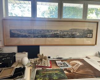 Long framed panoramic cityscape with assorted tabletop items below.