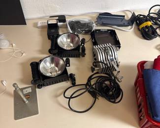 Portable lighting equipment, cords, and accessories arranged on a tabletop.