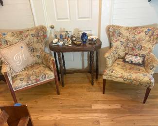 Two beautiful vintage floral upholstered accent chairs with wooden frames, accompanied by a classic wooden accent table. Also featuring assorted vintage figurines, decorative glassware, and collectibles. Pair-$250