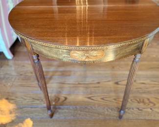 Vintage Sheraton-Style Round Mahogany Occasional Table with Floral Inlay — Elegant neoclassical round accent table featuring a polished mahogany-tone top, contrasting decorative apron with floral inlaid medallions, delicate stringing, and slender fluted tapered legs. Beautiful traditional proportions with warm wood tones and refined decorative details. Ideal as a living room accent table, bedside table, or small center table.