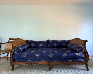 French Louis XV–style carved wood and cane daybed or canapé, featuring beautifully shaped cane ends, an ornate carved wooden frame, and striking blue upholstery