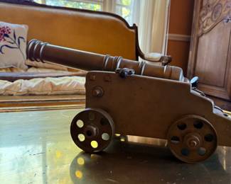 Vintage-Style Brass or Bronze-Tone Decorative Naval Cannon Model — Detailed miniature cannon featuring a turned barrel, traditional four-wheeled gun carriage, pierced metal wheels, and aged patina. Nautical and military-inspired decorative collectible.