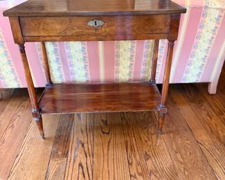 Antique French Louis XVI–Style Walnut One-Drawer Side Table — Charming rectangular occasional table featuring a warm wood finish, single full-width drawer with decorative brass keyhole escutcheon, slender turned and tapered legs, and a convenient lower display shelf. Elegant neoclassical proportions with age-appropriate surface wear and patina. Ideal as a bedside table, accent table, or small entryway console.