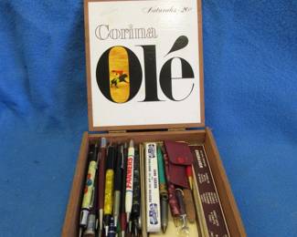 Lot 422. Corina Ole Cigar box and Assorted Pens (some with marketing).