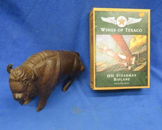 Lot 383. Carved desert ironwood bison weighing 11 lbs. 2 oz. and a die-cast metal bank featuring Wings of Texaco that appears. to be NIB