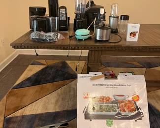 Blue and brown area rug. Solid wood dining table. Small kitchen appliances.