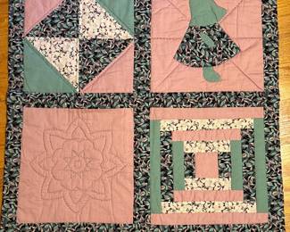 Handmade sampler quilt with four pieced blocks in pink and green