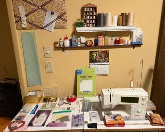 Sewing room work table with machine, notions and wall shelves