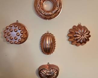 Set of copper gelatin molds hung on a wall