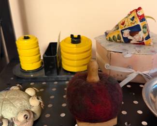 Yellow thread cone holders and a pincushion on a shelf